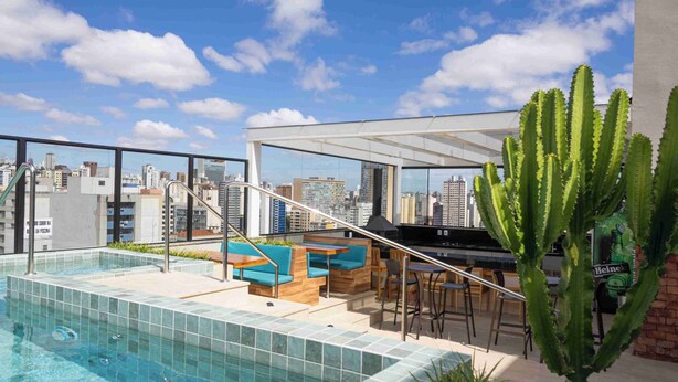 A rooftop pool area with a city view, seating, and a cactus plant. - Life Residence (Belo Horizonte)
