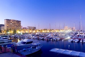 Boats docked at a tranquil marina adjacent to a multi-story building.