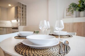A dining area with a round table set for two, featuring a woven placemat and white tableware.