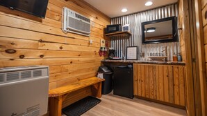 A compact kitchen with wooden paneling, a microwave, a sink, and a small refrigerator.