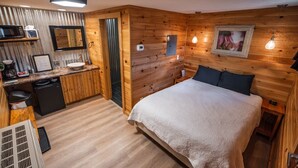 A wooden room with a bed, a sink, and a microwave.