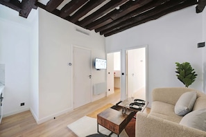 Un salon moderne avec un canapé, une table basse et un téléviseur fixé au mur.