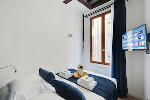 Une chambre d’hôtel avec un lit, une télévision, une fenêtre avec des rideaux et une vue sur l’extérieur.