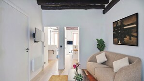 Ein modernes Wohnzimmer mit einer Couch, einem Flachbildfernseher, einem Gemälde und einem Blumentopf.