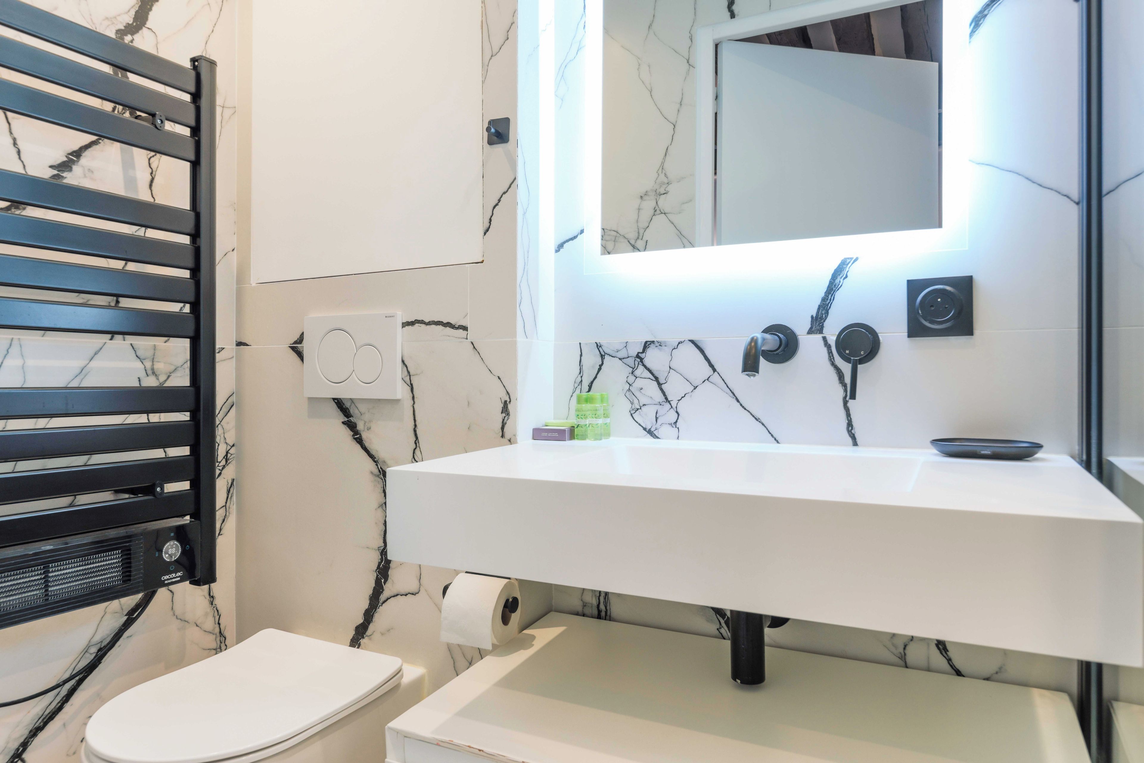 A bathroom with a white sink, a mirror, a towel rack, and a toilet.