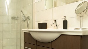 Une salle de bain moderne avec une douche à parois de verre, un lavabo blanc avec un miroir et des meubles en bois.