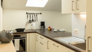 Une cuisine moderne dotée d’une lucarne, de meubles blancs, d’un plan de travail foncé et d’appareils électroménagers de base.