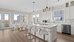 Una cocina moderna con una isla grande, taburetes de bar y vistas a la ciudad.