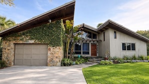A modern house with a stone facade, a garage, and a well-maintained lawn. - Historical NASA Home (Cape Canaveral)