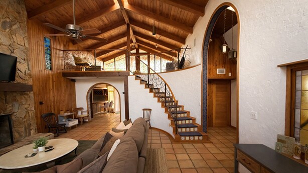 A spacious living area with a wooden staircase, stone walls, and a cozy seating arrangement. - Historical NASA Home (Cape Canaveral)