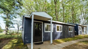 A single-story mobile home with a front porch, a door, and windows. - Cottages #7 Tree Tops, 2 Bedroom Cottage (Lake City)