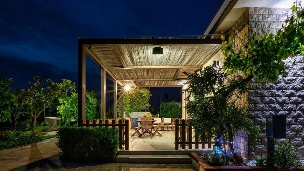 Un patio al aire libre con una pérgola de madera, una mesa de comedor y sillas.