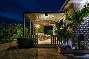 Ein möblierter Außenbereich mit Holzpergola, einem Esstisch und Stühlen.