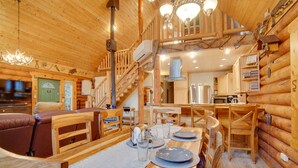 Ein Holzblockhaus-Interieur mit Essbereich, Treppe und Küche.