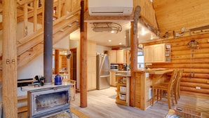 Ein Holzblockhaus-Interieur mit Küche, Essbereich und Kamin.