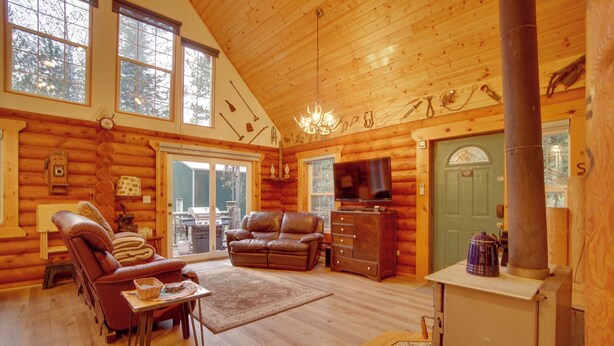 Ein Holzblockhaus-Interieur mit Kamin, Ledermöbeln und einem Fernseher.