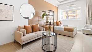 A modern living room with a sofa, a round coffee table, a bed, and a large window. - Silkhaus ASB Tower (Dubai)
