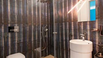 Une salle de bain moderne avec une douche à parois de verre, un lavabo blanc et des toilettes.