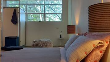 Une chambre à coucher avec un lit, une fenêtre, une lampe et une petite table.