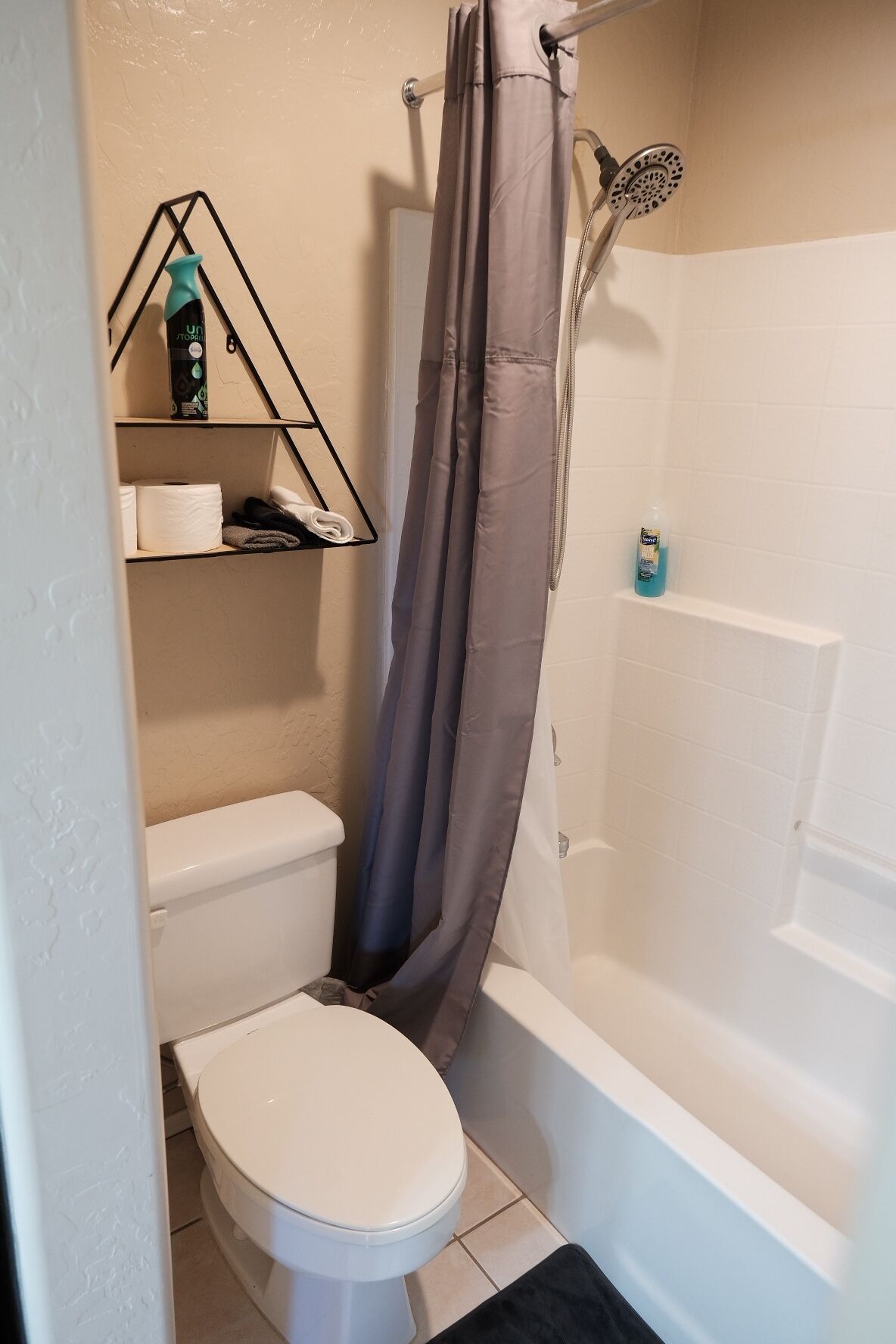 Een badkamer met toilet, douche en een plank met toiletartikelen.