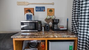 A kitchenette with a microwave, coffee maker, and a small refrigerator.