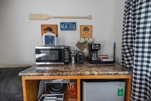 Una kitchenette equipada con microondas, cafetera y un refrigerador pequeño.