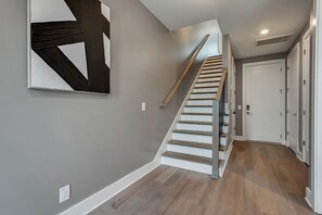 A modern interior with a wooden staircase, grey walls, and a white door.