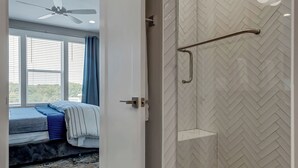 A modern bathroom with a glass shower enclosure, a herringbone tile pattern, and a visible showerhead. - 2 Luxe Side-by-Side Downtown Homes • Skyline Views (Nashville)