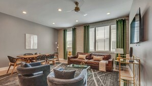 A modern living room with a sofa, armchairs, a coffee table, and a dining area with chairs and a table. - 2 Luxe Side-by-Side Downtown Homes • Skyline Views (Nashville)