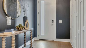 A hallway with a wooden console table, a mirror, and a vase with branches. - 2 Luxury New Homes | Near Broadway + Rooftop Views (Nashville)