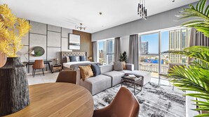 Een moderne hotelkamer met een groot raam, een bank, een eettafel en uitzicht op de stad.