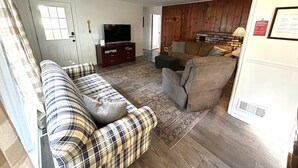 Un salon avec un canapé, des fauteuils, un téléviseur et une cheminée.