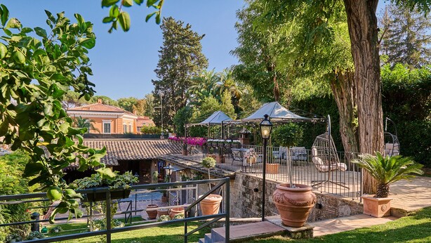 Une cour dotée d’une pergola, d’un espace salon et offrant une vue sur un bâtiment dont le toit est recouvert de tuiles.