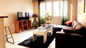 A living room with a TV, a coffee table, a sofa, and a dining table.