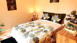 A bedroom with a bed, a nightstand, a lamp, and two wall-mounted paintings.