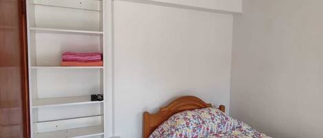 A bedroom with a bed, a wardrobe, and a door.