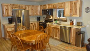 Une cuisine moderne avec des meubles en bois, des appareils électroménagers en acier inoxydable et un îlot central doté de sièges.