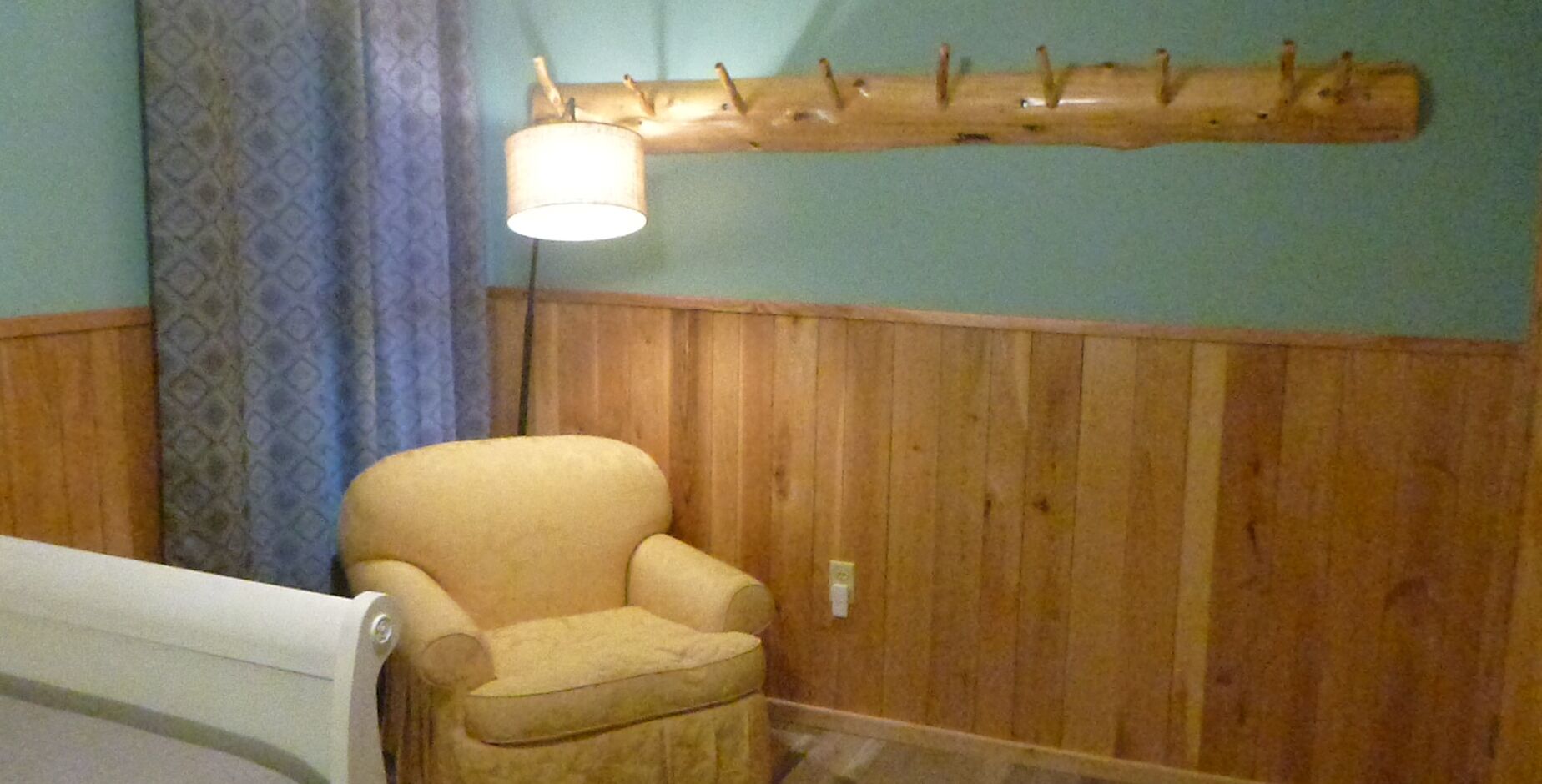 A room with a wooden wall, a chair, and a lamp.
