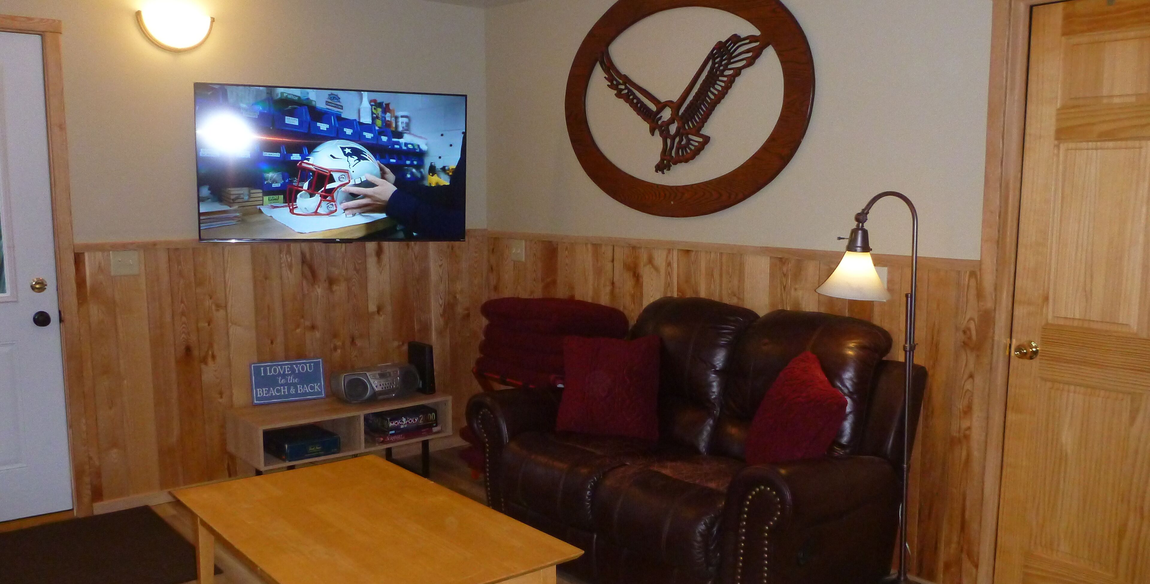 Una habitación con paneles de madera, un sofá de cuero, un televisor montado en la pared y un cartel en la pared.