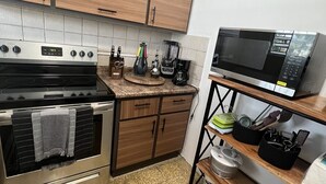Une cuisine avec des meubles en bois, une cuisinière en acier inoxydable, un four à micro-ondes et une machine à café.