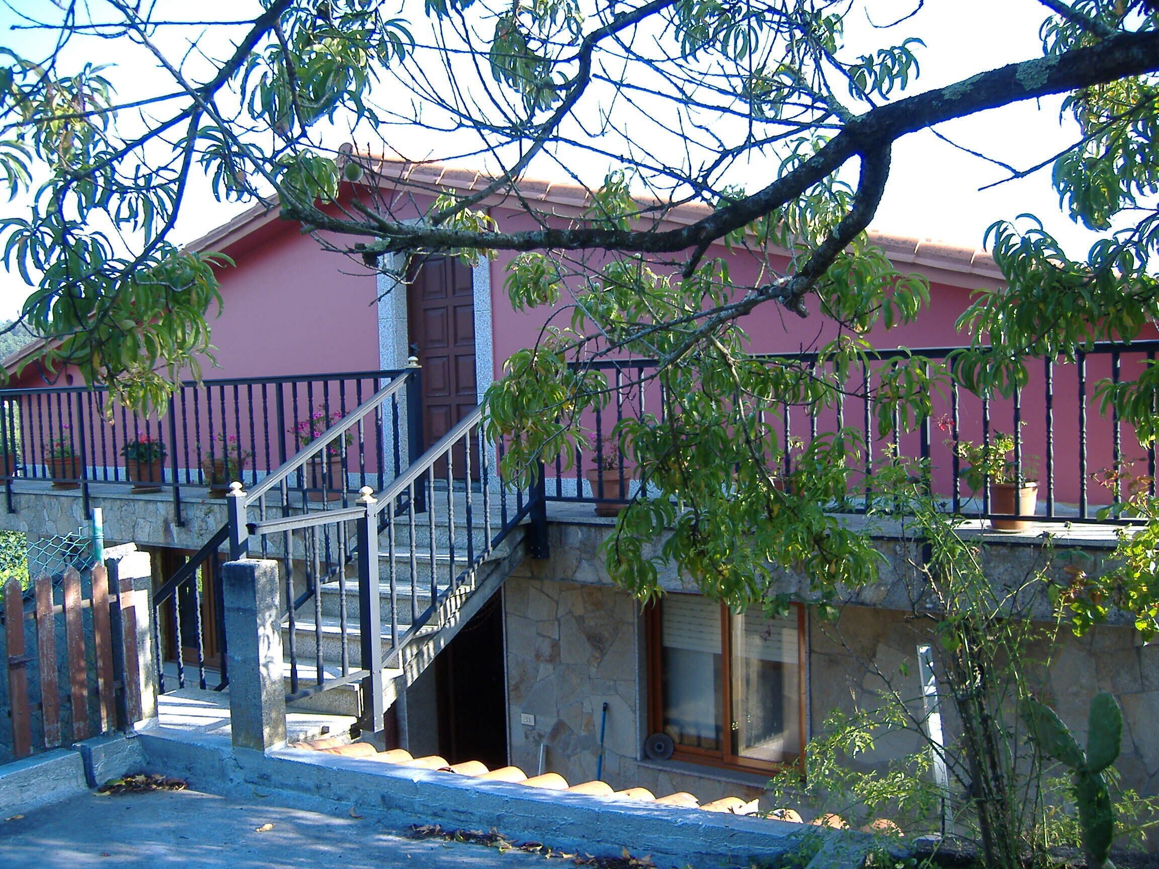 A two-story building with a red facade, a stone staircase, and a metal railing.