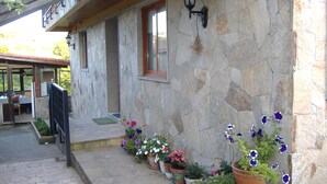 Un edificio de piedra con balcón, plantas en macetas y una ventana.