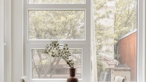 A room with a large window, two chairs, and a table with a vase. - Reside NoMa, a Wyndham Residence (Washington)
