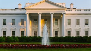 A large white building with a central fountain and columns, surrounded by a well-maintained garden with red flowers. - Reside NoMa, a Wyndham Residence (Washington)