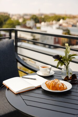 A table with a notebook, a cup of tea, a croissant, a vase with a plant, and sunglasses. - Reside NoMa, a Wyndham Residence (Washington)