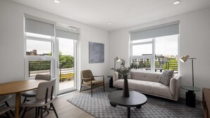 A modern living room with a sofa, chairs, a dining table, and a coffee table. - Reside NoMa, a Wyndham Residence (Washington)