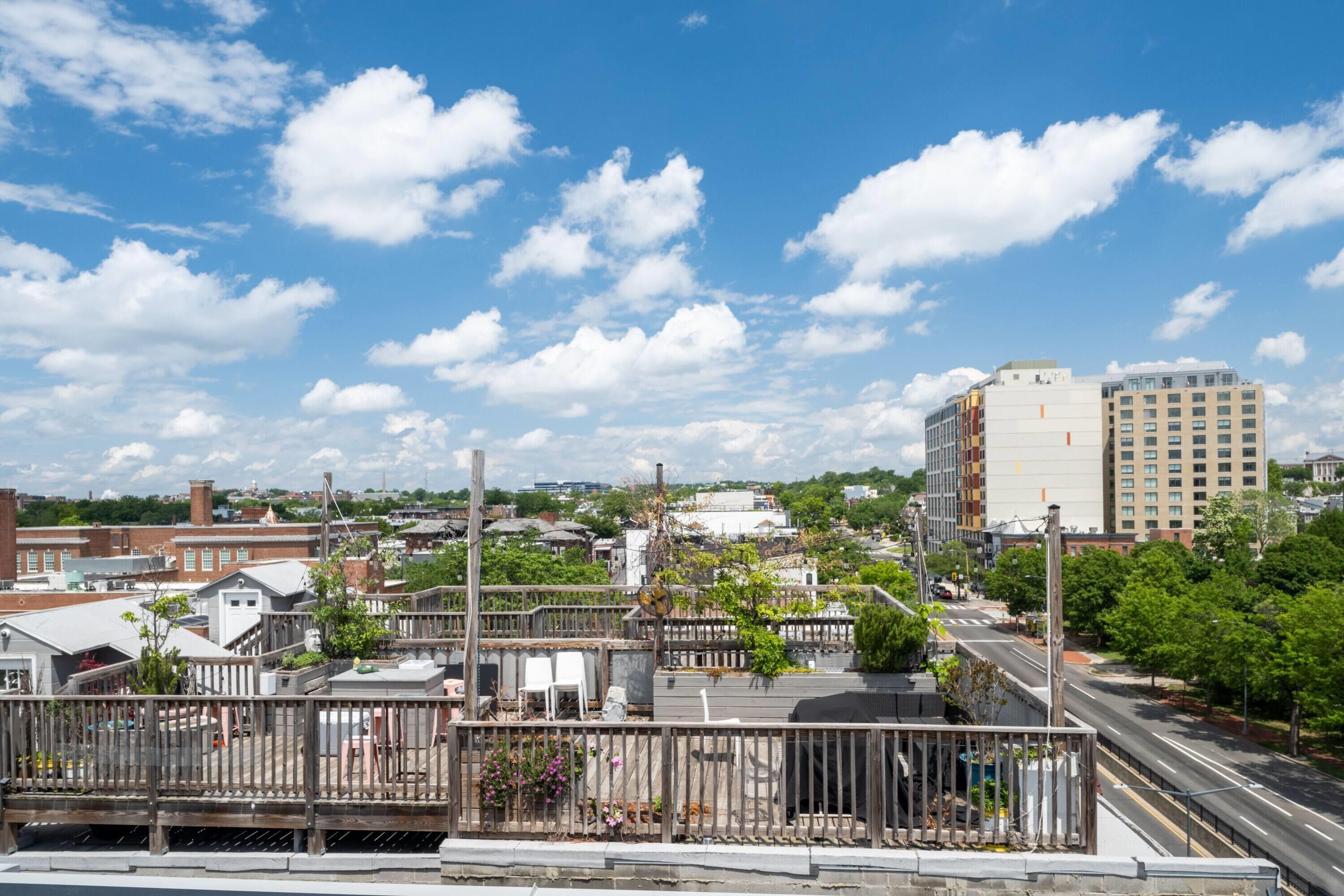 A cityscape with a prominent building in the background, a wooden fence in the foreground, and a clear blue sky.