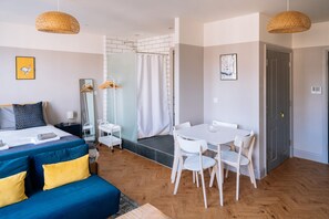A hotel room with a bed, a dining table with chairs, a shower area, and a bathroom. - Stunning Studio Flat with Scenic Views (Bath and North East Somerset)