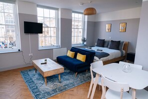 A modern room with a bed, a sofa, a dining table, and a TV mounted on the wall. - Stunning Studio Flat with Scenic Views (Bath and North East Somerset)
