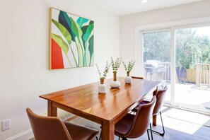 Un coin repas avec une table en bois, des chaises et des plantes en pot.